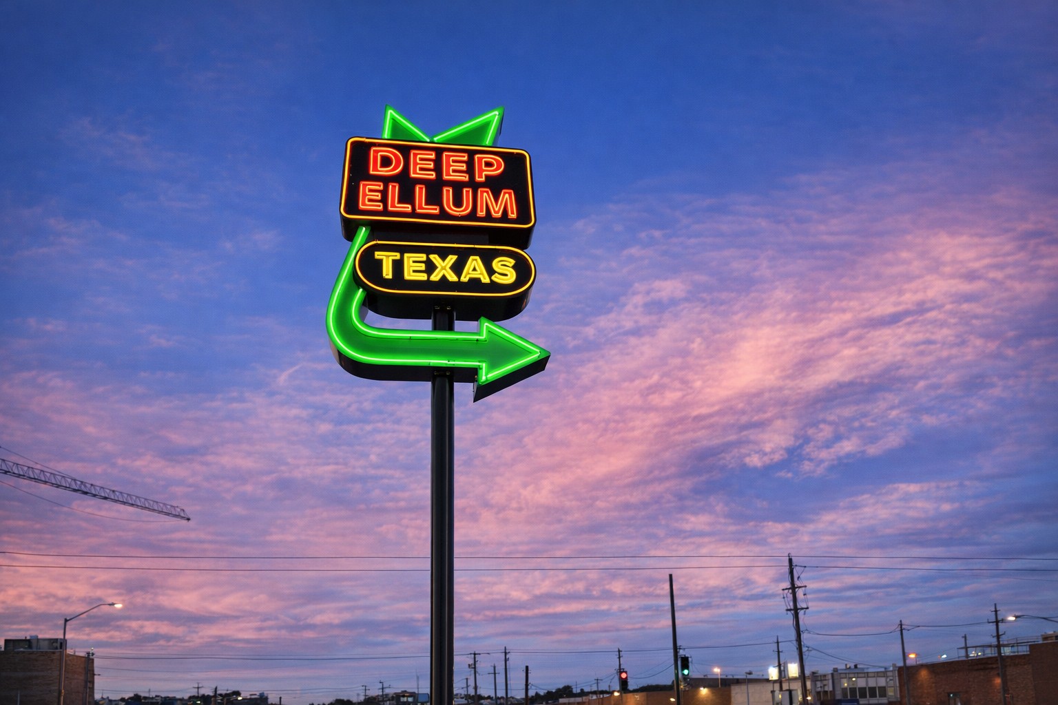 Deep Ellum neon sign beneath a colorful evening sky